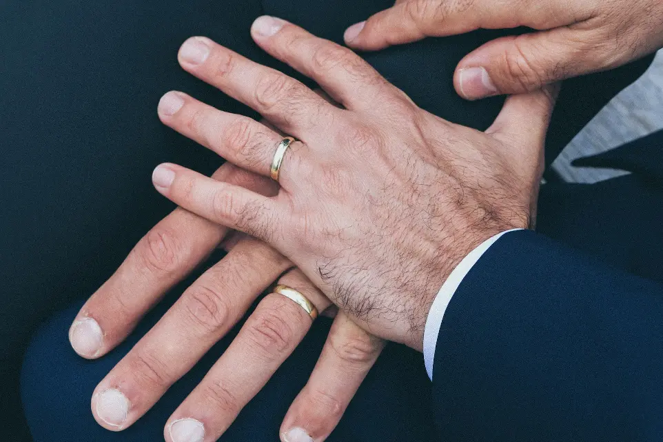 أيدي رجلين يرتديان خاتمين زفاف باللون الذهبي 